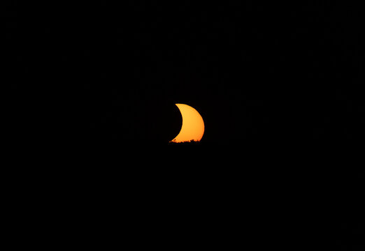 Partial solar eclipse over the horizon