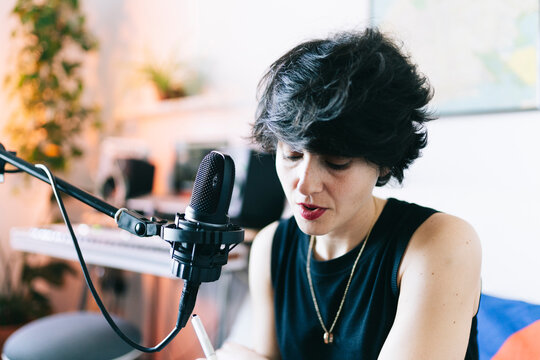 Woman recording music in home studio creating podcast