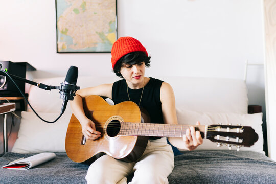 Woman playing acoustic guitar in home music studio