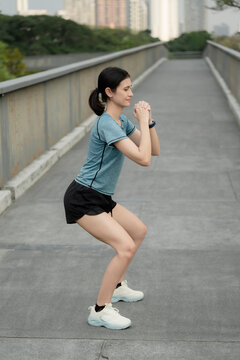 Young woman doing squat exercise on urban bridge, outdoor fitness training, strength workout, healthy lifestyle, active city living and bodyweight workout concept. woman, squat, workout,