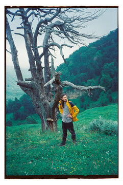 Man standing by a tree in a grassy area during daytime