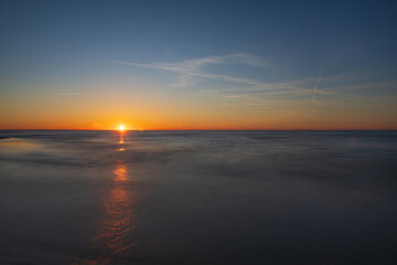 Obraz premium Minimalist ocean sunset landscape with smooth water reflection and vast golden horizon.