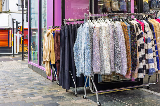 Colourful fluffy sweaters on outdoor clothing rack outside city