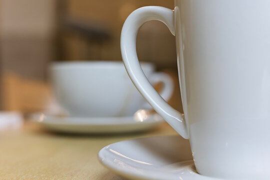 White ceramic coffee cups and saucers on cafe table close-up