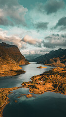 Vertical aerial view of a scenic fjord with wooden cabins and golden autumn mountains in northern Norway with copy space in sky © Quality by Simon