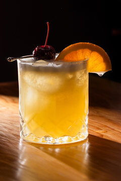 Beautiful Whiskey sour served on the rocks garnished with an orange slice and a dark cherry