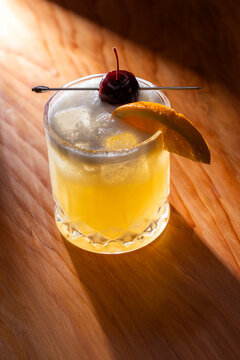 Beautiful Whiskey sour served on the rocks garnished with an orange slice and a dark cherry