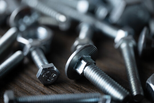 Metal bolts and screws on a wooden surface, showing industrial fastening and repair hardware items