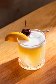 Beautiful Whiskey sour served on the rocks garnished with an orange slice and a dark cherry
