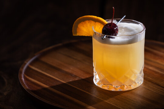 Beautiful Whiskey sour served on the rocks garnished with an orange slice and a dark cherry