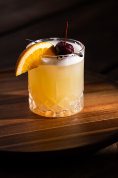 Beautiful Whiskey sour served on the rocks garnished with an orange slice and a dark cherry