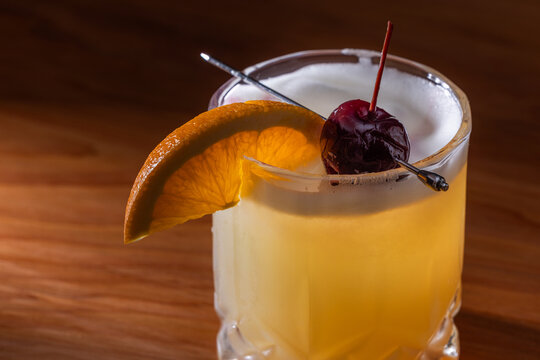 Beautiful Whiskey sour served on the rocks garnished with an orange slice and a dark cherry