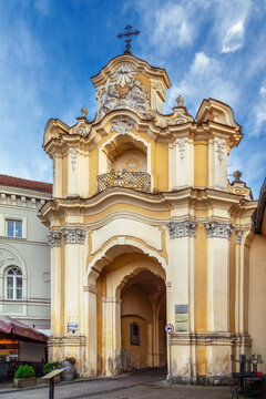 View of the entrance arch at the Monastery of the Holy Trinity in Vilnius, Lithuania. Baroque stone architecture and cloudy sky
