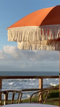 Orange vintage parasol with fringe on a seaside terrace overlooking the ocean