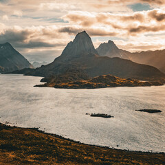 Panoramic aerial view of a dramatic mountain peak and fjord under golden sunlight in northern Norway © Quality by Simon