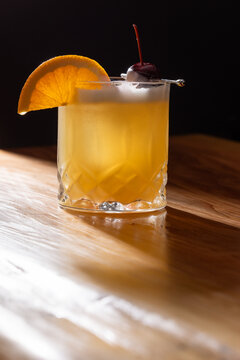 Beautiful Whiskey sour served on the rocks garnished with an orange slice and a dark cherry