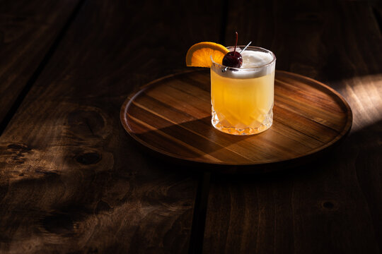 Beautiful Whiskey sour served on the rocks garnished with an orange slice and a dark cherry