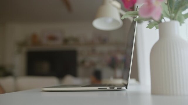 Man's hands opening a laptop on a white desk to start his workday from a cozy home office, ready for online meetings, browsing the internet, or checking emails