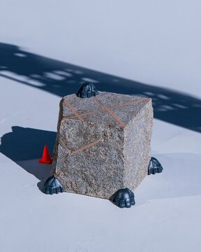 Stone grey granite podium with a raw texture in an empty parking garage, featuring a red traffic cone for a minimalist product mockup