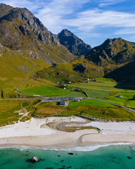 Vertical aerial view of a white sand beach with turquoise water and green mountains under a blue sky in northern Norway © Quality by Simon