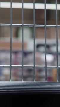 Vertical video macro shot showing the steel wire mesh of a shopping cart in a supermarket with blurred store background