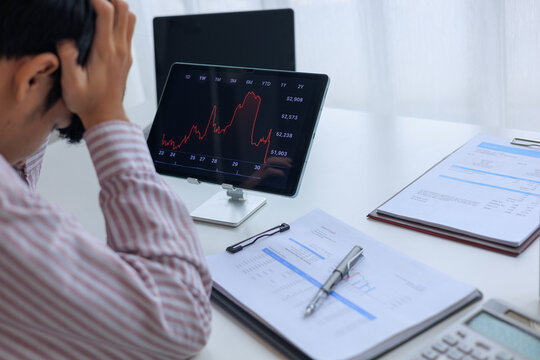Stressed Investor Looking at Market Crash Stock Chart on Tablet in Office.