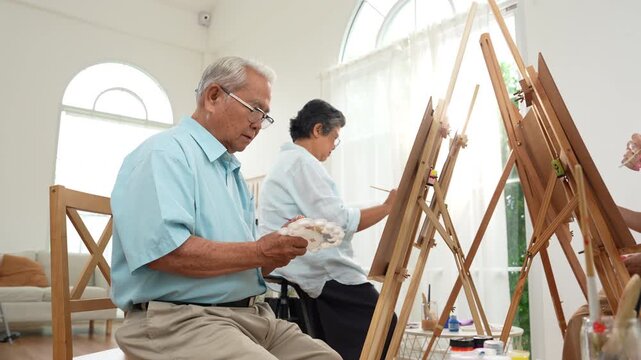 Group of elderly Asian friends enjoying a painting class at home, creating art together in a warm setting. Active aging, creativity, social connection, wellbeing, and senior lifestyle.