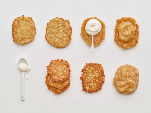 Hanukkah latkes collection featuring golden fried potato pancakes with sour cream and applesauce, isolated on a white background for menus