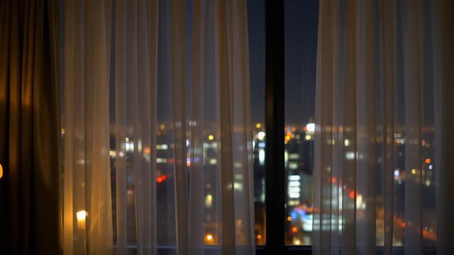 Hotel curtain moving with city light behind