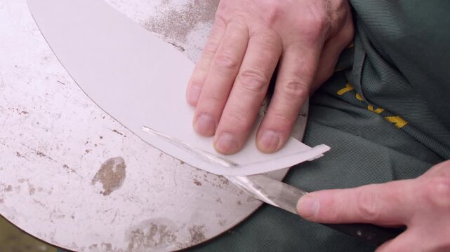 Diy artisan. Craft tool. Unrecognizable professional master hands using metal knife trimming leather material for shoe manufacturing.