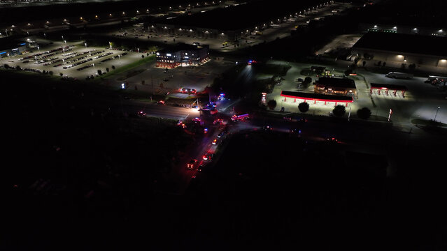 Greencastle, Pennsylvania, United States - 08 October 2025: Aerial view of emergency vehicles with flashing lights at a night-time intersection, surrounded by commercial buildings.