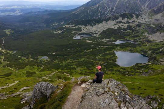 Female hiker sitting on rocky ridge above mountain tarns in Tatra Mountains