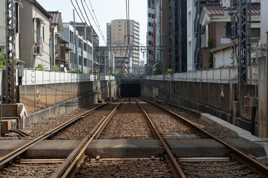 住宅街の間に切り拓かれた線路が地下のトンネルへと向かう、奥行きのある鉄道風景