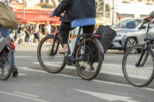 Cyclists riding electric bicycles through urban traffic, promoting sustainable transportation and eco-friendly mobility in Paris