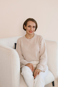Smiling woman sitting white armchair cozy room background