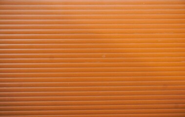 Abstraktes Motiv mit orangefarbenem Garagentor mit Querstreifen als Hintergrund © Anette