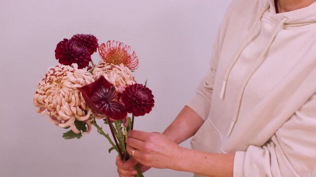Blossom plant. Seasonal bouquet. Unrecognizable female floral designer arranging chrysanthemum flower composition in workshop.