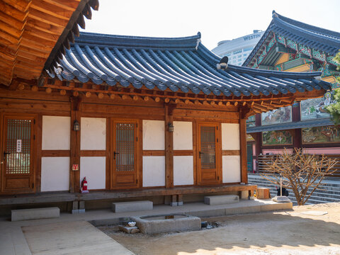 View of Gyeongbokgung Palace featuring traditional wooden architecture with intricate tiled roofing and white walls in a serene courtyard setting in Seoul, Seoul, South Korea.