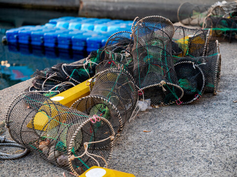 View of fishing traps and nets resting on a concrete pier with blue floating buoys in the background in Busan, Busan, South Korea.