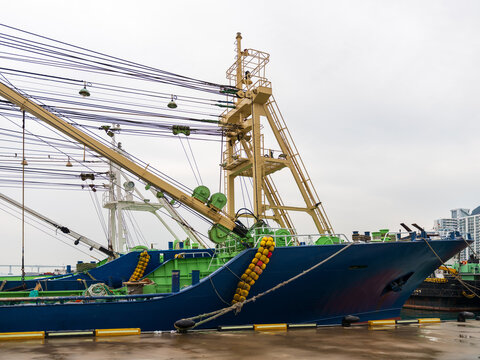 View of a commercial fishing trawler with blue hull and green rigging docked at the harbor in Busan, Busan, South Korea.