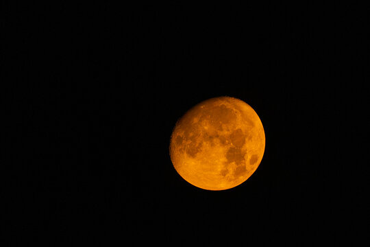 View of the moon glowing with an orange hue against the dark night sky in Pakistan.