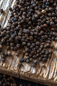 Close-up of black peppercorns scattered on rustic wooden surface