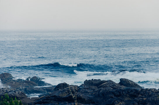 Waves crashing over dark volcanic rocks along the ocean shore
