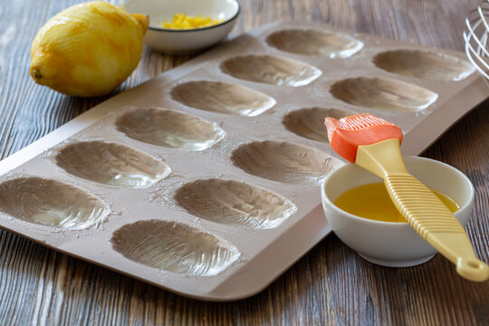 Baking preparation with lemon, greased mold, and brush on wooden table