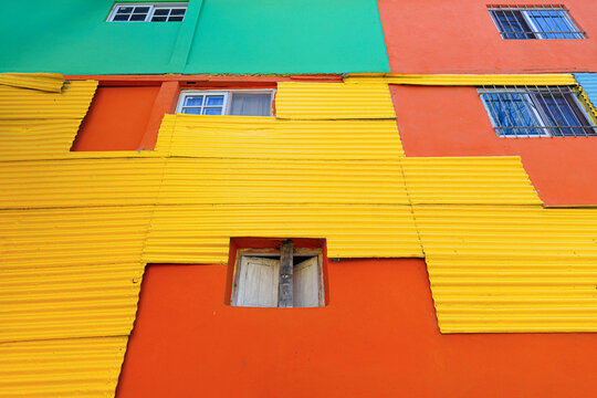 View of the vibrant colorful corrugated metal walls of the Caminito in La Boca, featuring bright yellow, orange, and green panels in Buenos Aires, Ciudad Autonoma de Buenos Aires, Argentina.