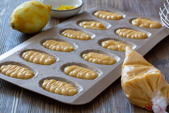 Lemon-flavored pastry dough in metal mold on wooden kitchen table.