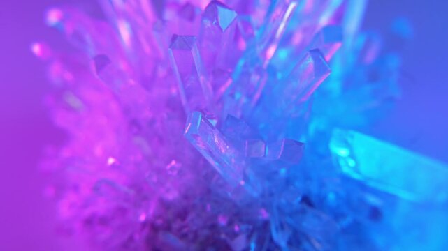 A real crystal. The grown crystal rotates on an illuminated turntable. A scientific experiment and chemical study. A beautiful background or screensaver. Pink and blue.