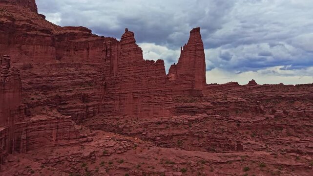 Dramatic aerial perspectives reveal towering mudstone spires and rugged fins below moody evening skies at Fisher Towers near Moab Utah