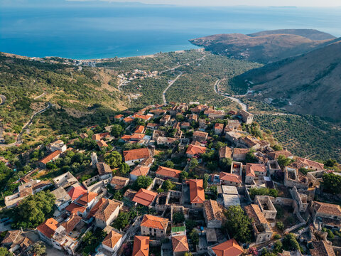 Drone view of small Albanian village built on rocky hillside, real Mediterranean landscape and rural lifestyle illustration in QEPARO FUSHE, ALBANIA