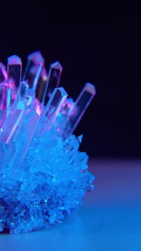 A mysterious, magical, genuine crystal. The grown crystal rotates on an illuminated turntable. A scientific experiment and chemical study. A beautiful background or screensaver. Blue and pink.